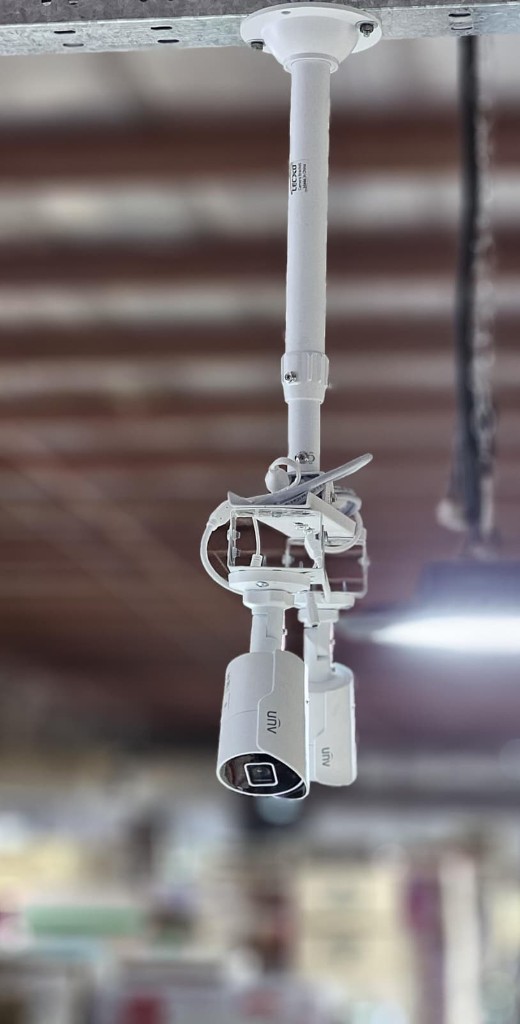 Twin Uniview bullet CCTV cameras pole-mounted on high warehouse ceiling in Germany